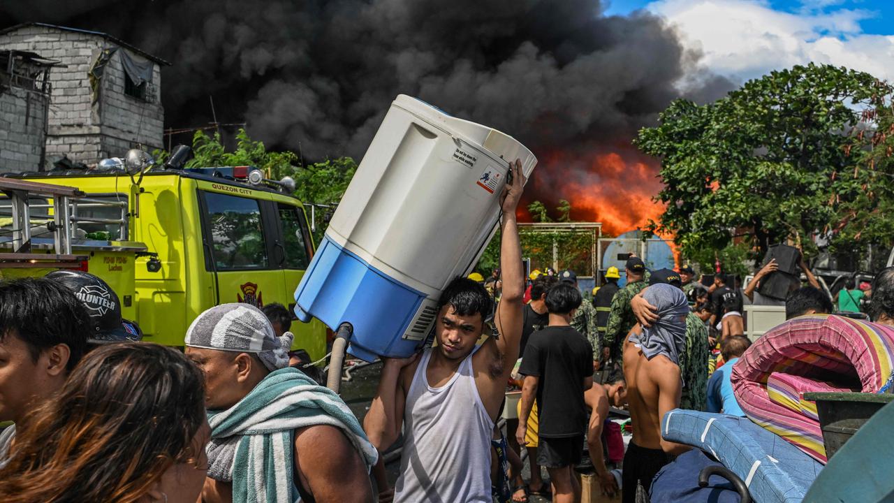 Residents carry their belongings and thousands of homes burned. (Photo by JAM STA ROSA / AFP)