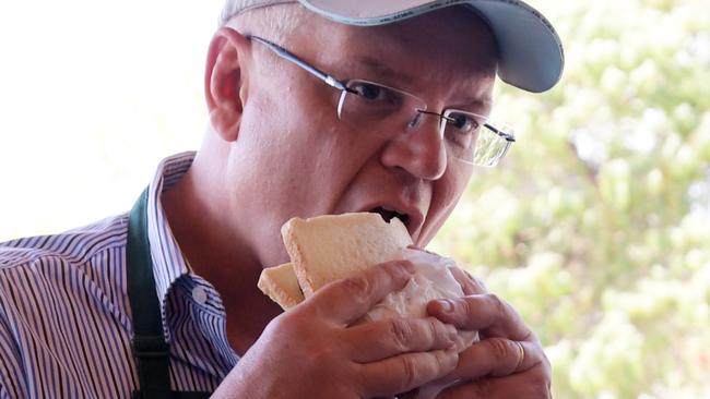 Prime Minister Scott Morrison takes a bite of a sausage sandwich — one white bread. Picture: Tracey Nearmy/News Corp