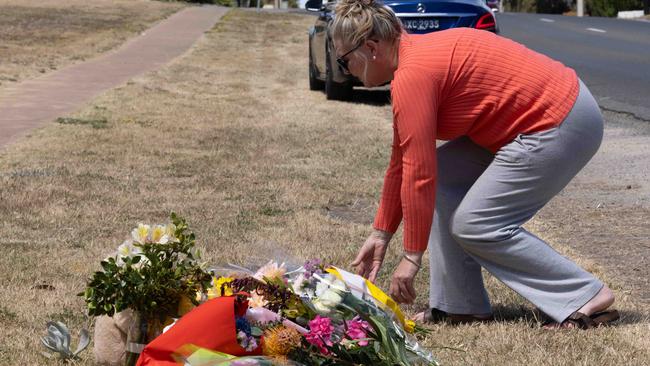 A mourner lays flowers in tribute to Charlie Stevens at the scene of the crash. Picture: Ben Clark