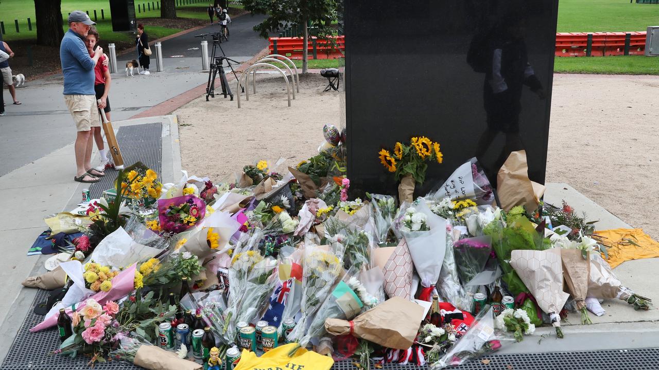 People lay flowers and other items at the statue of Shane Warne at the Melbourne Cricket Ground. Picture: NCA NewsWire / David Crosling