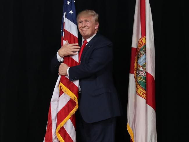 Donald Trump hugs the American flag as he arrives for a campaign rally in Tampa, Florida. Picture: Joe Raedle/Getty Images/AFP