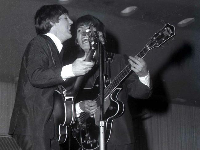 Paul McCartney and George Harrison perform during The Beatles' show of 1964.