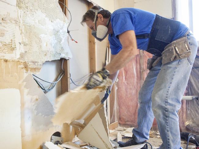 Man tearing out old kitchen during home renovations.