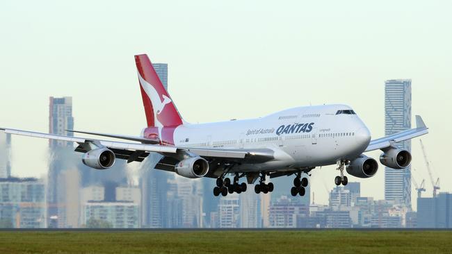 QANTAS plane landing at Brisbane Airport with Brisbane City buildings in background. Photographer: Liam Kidston.