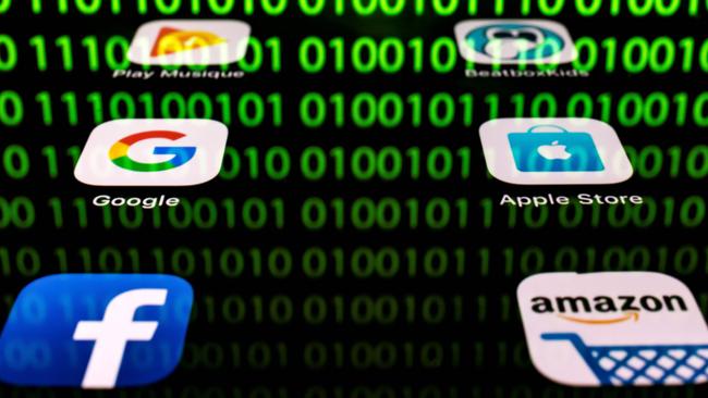 (FILES) In this file photo taken on April 20, 2018 shows an illustration picture in Paris shows apps for Google, Amazon, Facebook, Apple (GAFA) and the reflexion of a binary code displayed on a tablet screen. - The OECD published on October 9, 2019, its suggestions for a "unified approach" on fairly taxing digital giants to break a deadlock in a dispute that has raised tensions between the United States and some EU allies. (Photo by Lionel BONAVENTURE / AFP)