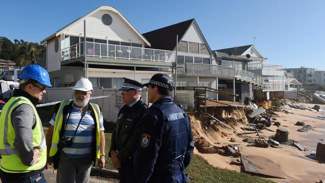 Warringah Council group manager a natural environments Todd Dickinson (left) and consultant coastal engineer specialist Angus Gordon with speak to police during an inspection of damaged beachfront homes. Picture: AAP