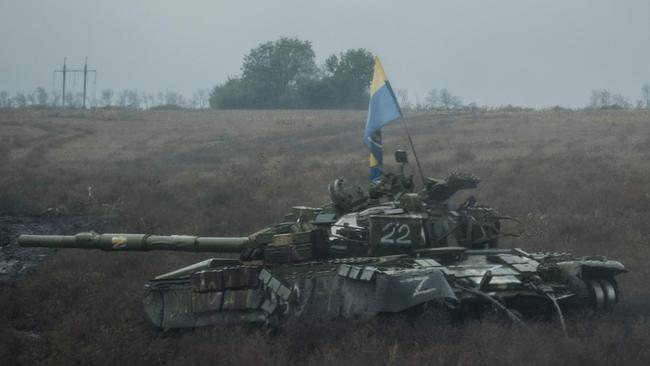 A Ukrainian flag is put on an abandoned Russian tank near Dolina in the Donetsk region, on October 10