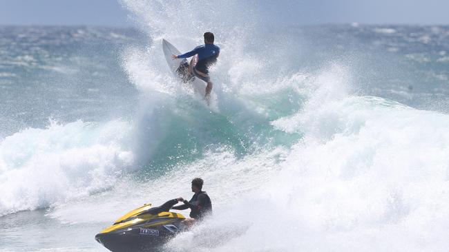 Surfers enjoy the massive waves at Currumbin, with a bit of help from a jet ski. PIC: Adam Head