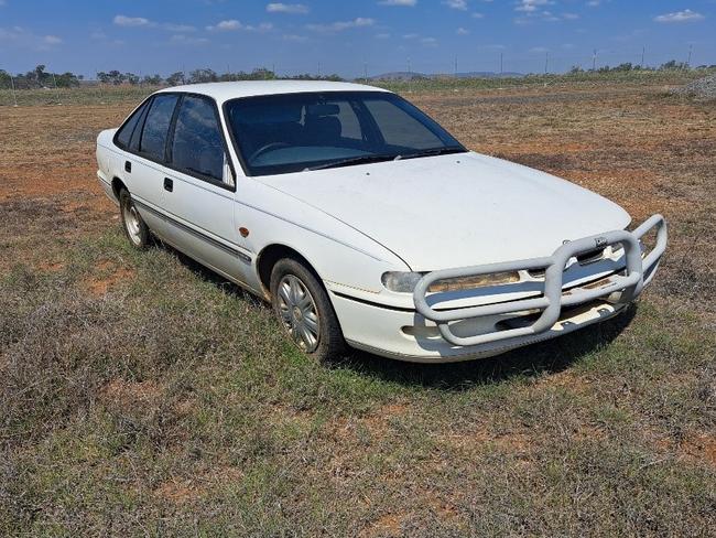 Unregistered, four door, white Holden Commodore sedan.