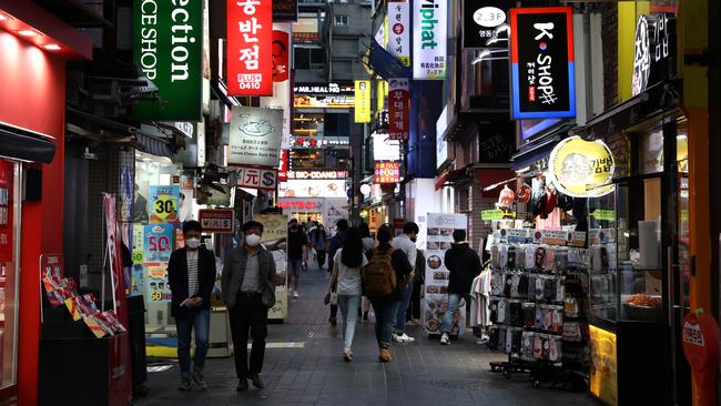 People walk along a street in face masks in Seoul during the week amid a return to their daily routines but an outbreak has forced closure of nightclubs. Picture: Getty Images