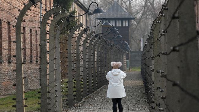 A visitor walks among barbed wire and prison barracks at the former Auschwitz I concentration camp in Oswiecim, Poland.