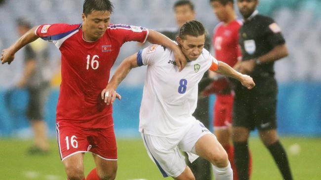 SYDNEY, AUSTRALIA - JANUARY 10: Server Djeparov of Uzbekistan is challenged by Cha Jong Hyok of DPR Korea during the 2015 Asian Cup match between Uzbekistan and DPR Korea at ANZ Stadium on January 10, 2015 in Sydney, Australia. (Photo by Matt King/Getty Images)