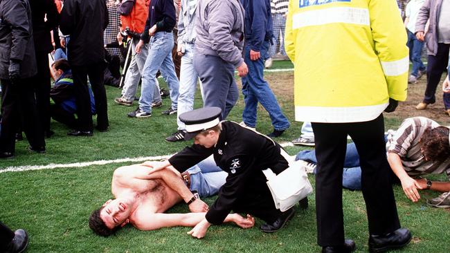 Emergency sevices personnel help soccer fans on the pitch at Hillsborough in 1989