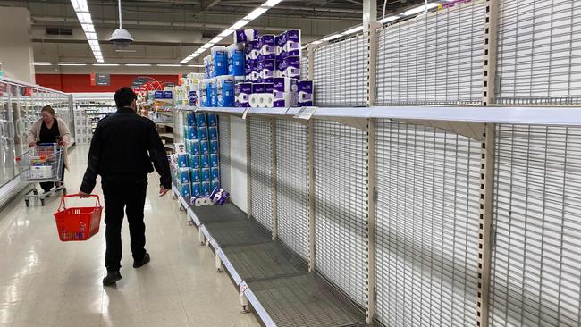 A shopper walks past near-empty shelves of toilet paper at a supermarket in a Melbourne on the weekend. Picture: AFP