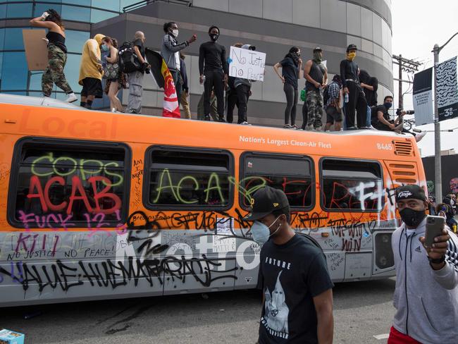 Demonstrators stand on top of a damaged bus in the Fairfax District as they protest the death of George Floyd. Picture: Mark Ralston