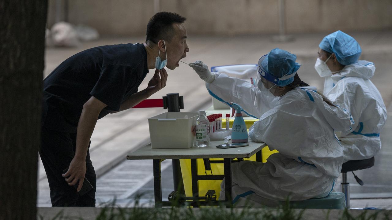 BEIJING, CHINA -JUNE 14: A man is given a nucleic acid test by a health worker, after a recent COVID-19 outbreak, at a testing site on June 14, 2022 in Beijing, China. China's capital is working to control a fresh COVID-19 cluster after dozens of people linked to a local nightclub tested positive for the virus. After easing restrictions earlier in the week, local authorities have initiated local mass testing and targeted lockdowns in addition to mandated proof of a negative PCR test within 72 hours to enter most public spaces and entertainment establishments and bars in some districts have been ordered to close in an effort to maintain the country's zero COVID strategy. (Photo by Kevin Frayer/Getty Images)