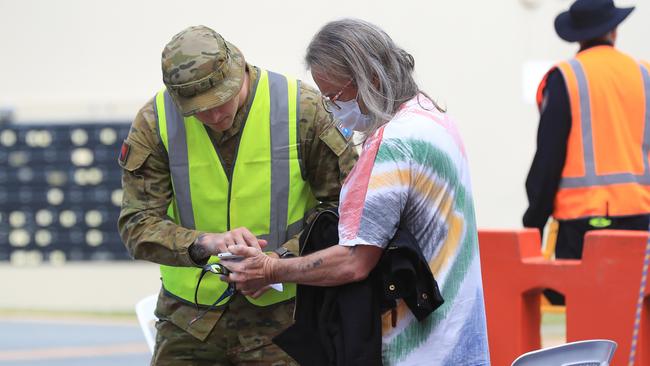 An ADF officer checking the details of a person crossing the border at Griffith Street in Coolangatta. Picture: Adam Head.