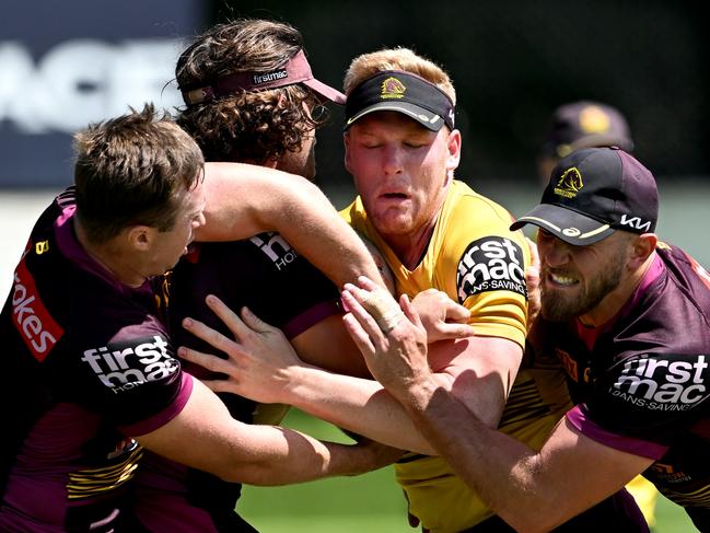 BRISBANE, AUSTRALIA - MARCH 07: Thomas Flegler is wrapped up by the defence during a Brisbane Broncos NRL training session at Clive Berghofer Centre on March 07, 2022 in Brisbane, Australia. (Photo by Bradley Kanaris/Getty Images)