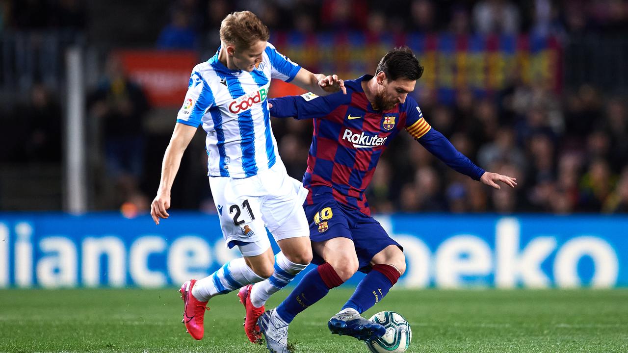 Martin Odegaard battles Lionel Messi.