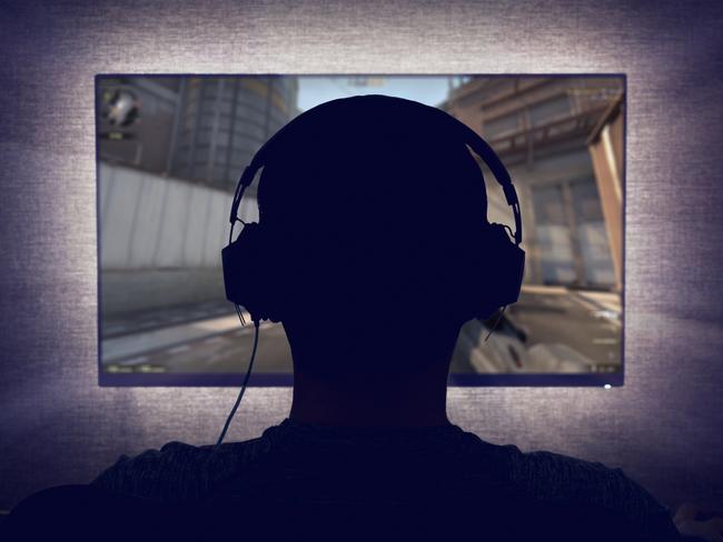 Gamer in headphones sits in front of a blank monitor in dark room