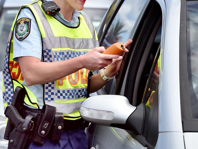 ** WARNING - POLICE OFFICER HAS ASKED FOR NAME NOT TO BE PUBLISHED AS IT MAY JEOPARDISE A FUTURE APPOINTMENT. PLEASE USE GENERIC CAPTION ** Senior Constable Jessica Brooks (R) conducts a breath alcohol test on Matt Salmon during a RBT operation at Terrigal on Tuesday 27th March 2018. Police will be out in force across the Central Coast over the Easter long weekend. (AAP IMAGE / Troy Snook)