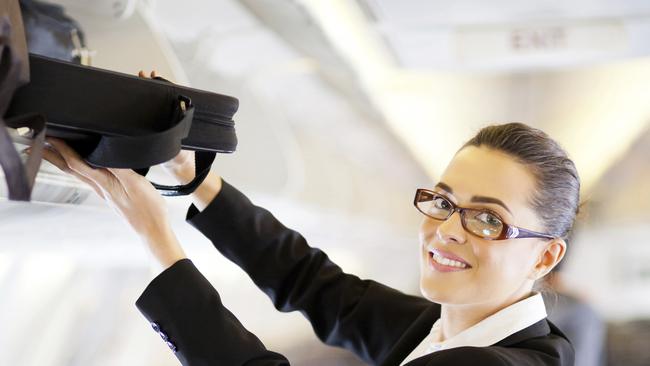 pretty businesswoman putting her luggage into overhead locker on airplane