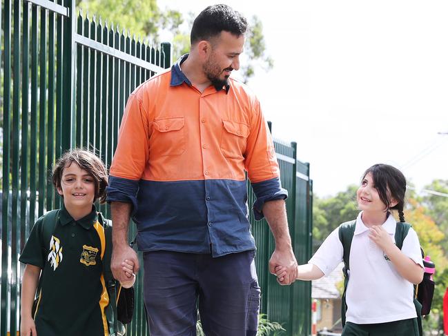 Moustafa Sanoussi with his kids Laith 7, and Amira 5. Parents collect their kids from Georges Hall Public School after the NSW Government announced new school guidelines. Picture Rohan Kelly