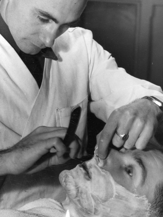 A city barber shaves a customer in 1947.