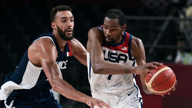 USA's Kevin Wayne Durant (R) dribbles the ball past France's Rudy Gobert in the men's final basketball match between France and USA during the Tokyo 2020 Olympic Games at the Saitama Super Arena in Saitama on August 7, 2021. (Photo by Aris MESSINIS / AFP)