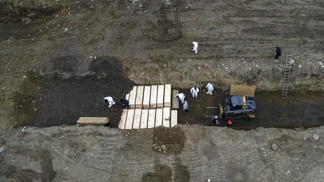 Workers wearing personal protective equipment bury bodies in a trench on Hart Island in the Bronx borough of New York. Picture: AP