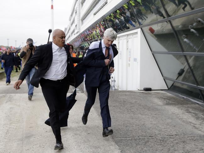 On the run ... Air France executive Pierre Plissonnier runs away from the demonstrators with the help of a security officer. Picture: AFP/Kenzo Tribouillard