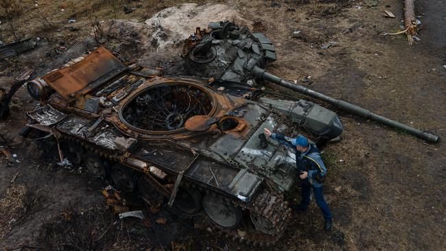 A man places a boot to take a photograph of a destroyed Russian military tank in April in Dmytrivka, Ukraine. Picture: Getty Images