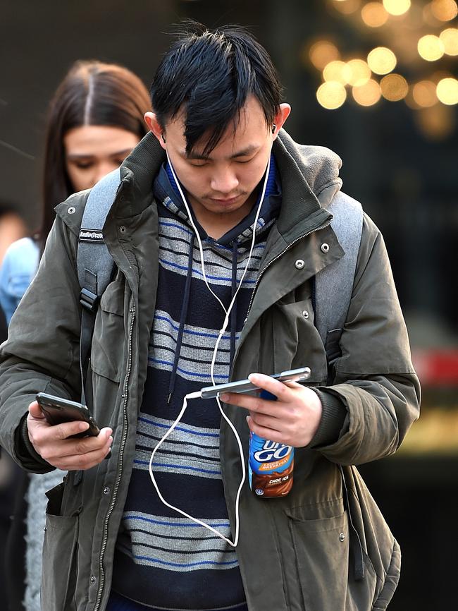 People in the city looking and listening to their phones as they make their way through the CBD Melbourne. Picture: Nicole Garmston