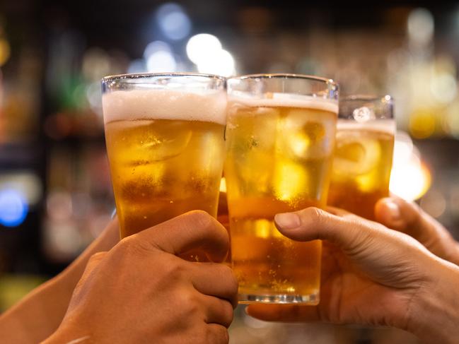 Group of happy friends drinking and toasting beer at brewery bar restaurant - Friendship concept with young people having fun together at cool vintage pub - Focus on middle pint glass