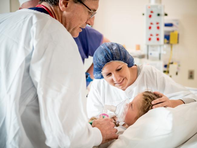 Scarlett is comforted by her mother Sasha as she's put to sleep by anaesthesiologist Dr Rob McDougall. Picture: Jake Nowakowski