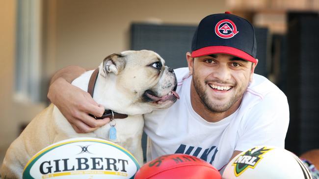 Former Brisbane Broncos NRL player Karmichael Hunt, who quit the NRL and is heading off to France to play rugby union for six months, before taking up his contract to play AFL with the fledgling Gold Coast club in 2011 season, pictured with his dog Buddha and balls from three football codes at his Calamvale home in Brisbane.