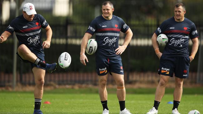 Brett Morris, centre, and Josh Morris, right, watch Mitchell Aubusson put boot to ball during a Roosters training session at Kippax Lake Field on Thursday. Picture: AAP