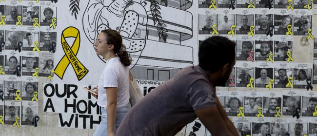 People pass by a wall covered with photos of hostages held in the Gaza Strip. Picture: Getty Images