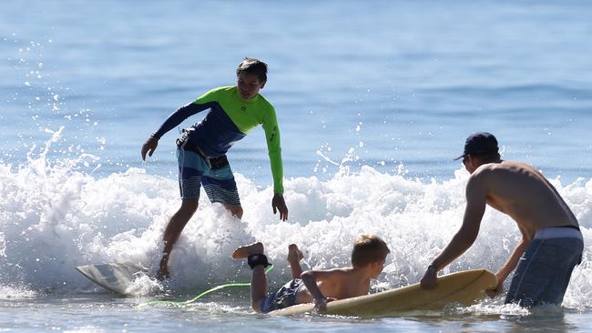 Kiran Barry (left), 12, enjoys surfing while a young surfer gets some lessons on a bright and sunny day in Burleigh. Picture: Regi Varghese