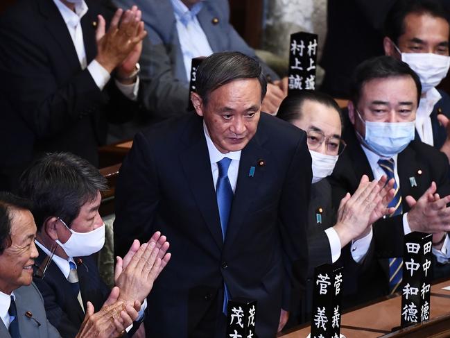 TOPSHOT - Newly elected leader of Japan's Liberal Democratic Party (LDP) Yoshihide Suga (C) is applauded after he was elected as Japan's prime minister by the Lower House of parliament in Tokyo on September 16, 2020. - Japan's parliament votes on September 16 for the country's next prime minister, with powerful cabinet secretary Yoshihide Suga all but assured the top job, as Shinzo Abe ends his record-breaking tenure. (Photo by CHARLY TRIBALLEAU / AFP)