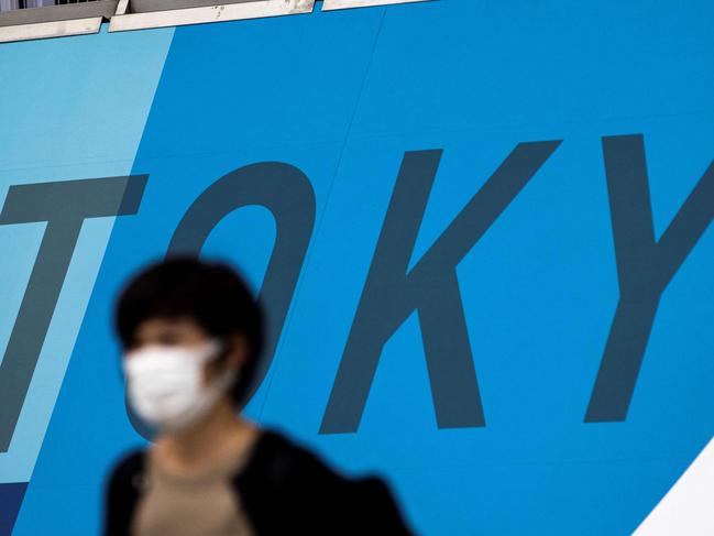 A woman wearing a face mask walks past a Tokyo 2020 Olympic Games decoration at Tokyo Big Sight, the site of the International Broadcast Centre (IOC) and Main Press Centre (MPC) for the Tokyo 2020 Olympic and Paralympic Games, in Tokyo on July 9, 2021, a day after Japan's government announced a new virus state of emergency stretching throughout the Tokyo Olympics. (Photo by Behrouz MEHRI / AFP)