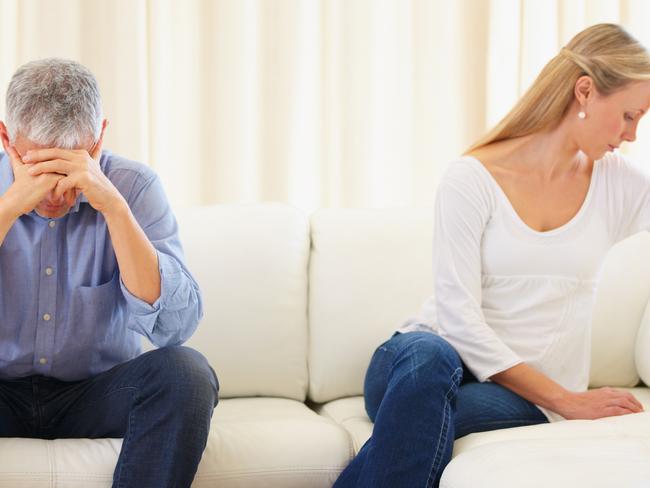 Upset married couple sitting on the sofa after a disagreement; argument generic