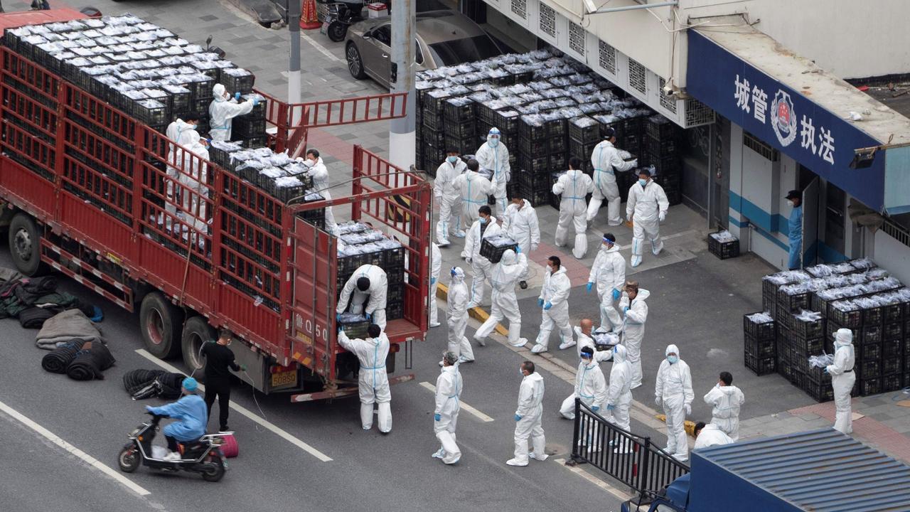 People wearing personal protective equipment as they transfer daily food supplies and necessities for local residents in lockdown in Shanghai. Picture: AFP/China OUT