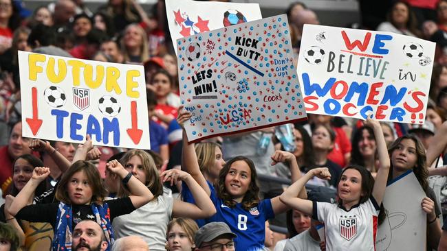 Young fans cheer and hold up signs before the start of the SheBelieves Cup football match between USA and Australia at State Farm Stadium in Glendale, Arizona, on February 23, 2025. (Photo by Patrick T. Fallon / AFP)