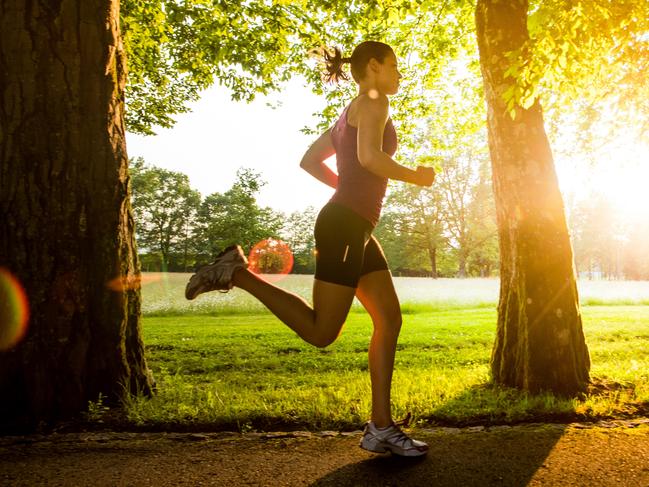 Young woman jogging in park at sunset.