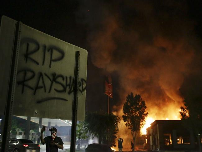 "RIP Rayshard" is spray painted on a sign as flames engulf a Wendy's restaurant in Atlanta. Picture: AP