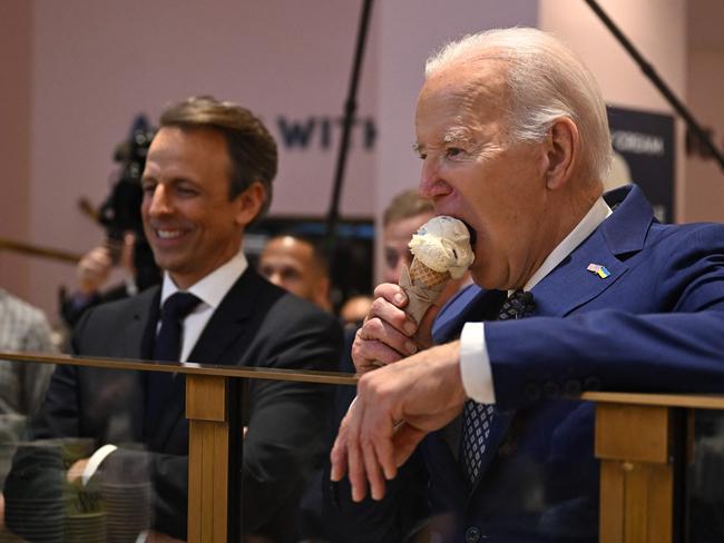 TOPSHOT - US President Joe Biden (R), flanked by host Seth Meyers (L), eats an ice cream cone at Van Leeuwen Ice Cream after taping an episode of "Late Night with Seth Meyers" in New York City on February 26, 2024. (Photo by Jim WATSON / AFP)