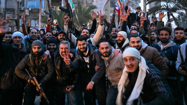 Local residents cheer as the gather on a street in the Damascus suburb of Jaramana on December 8. Picture: AFP