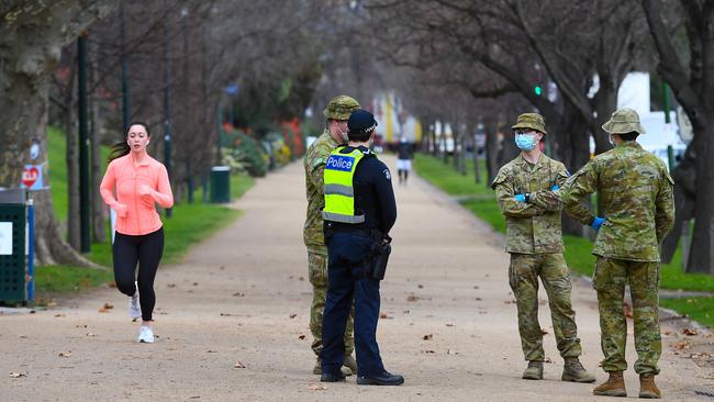 Police officers and soldiers patrol a popular running track in Melbourne on Tuesday. Picture: AFP