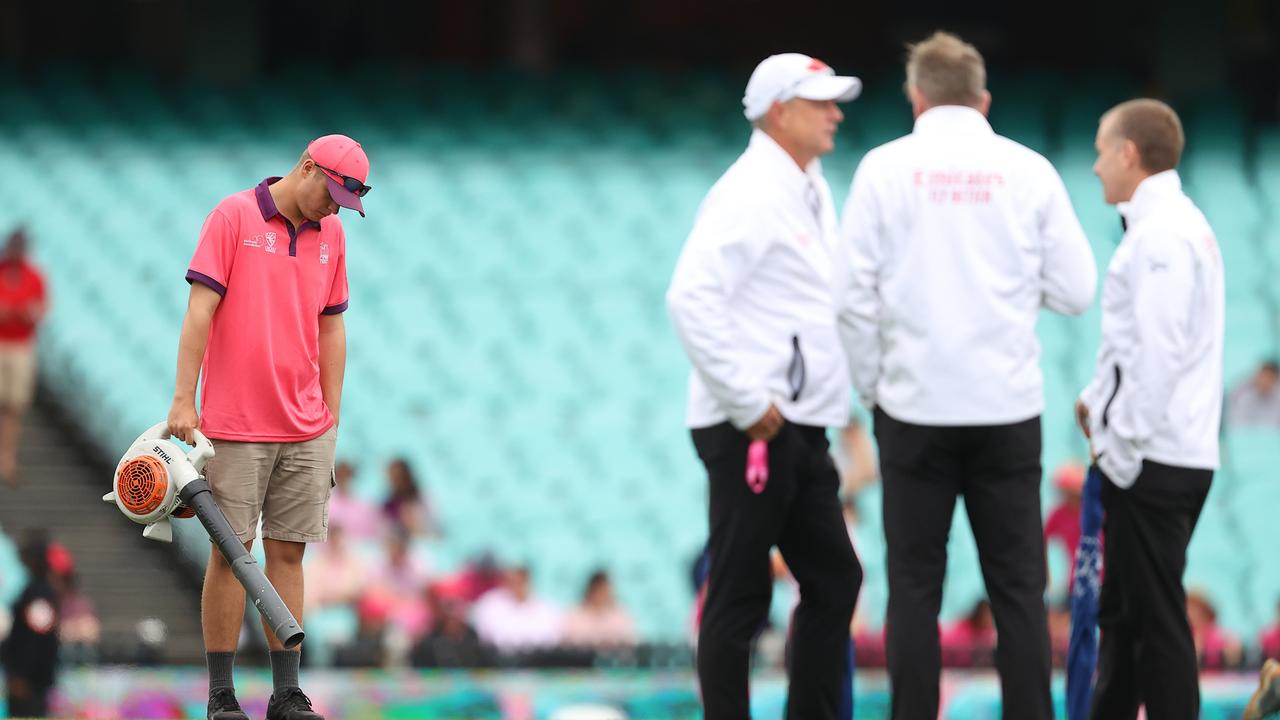 Ground staff work to dry the field as umpires speak during day four. Picture: Getty